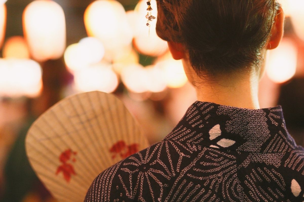 People wearing yukata walking under lantern lights at a local Japanese summer festival